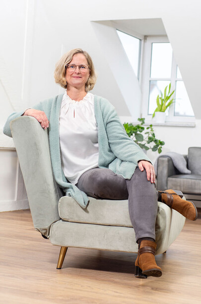 Als Beraterin und Coach ist Kerstin Angermeier ganz entspannt. Sie sitzt lächelnd auf einem hellen Sofa.
